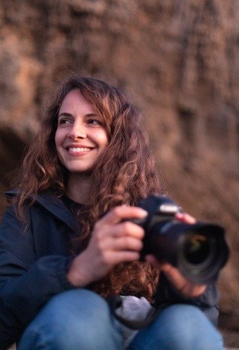 Elena sitting on a rock with a camera